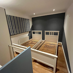 Twin bedroom with feature navy wall behind white bed frames