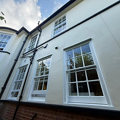 Cream stucco facade with freshly painted white sash windows and black downpipes