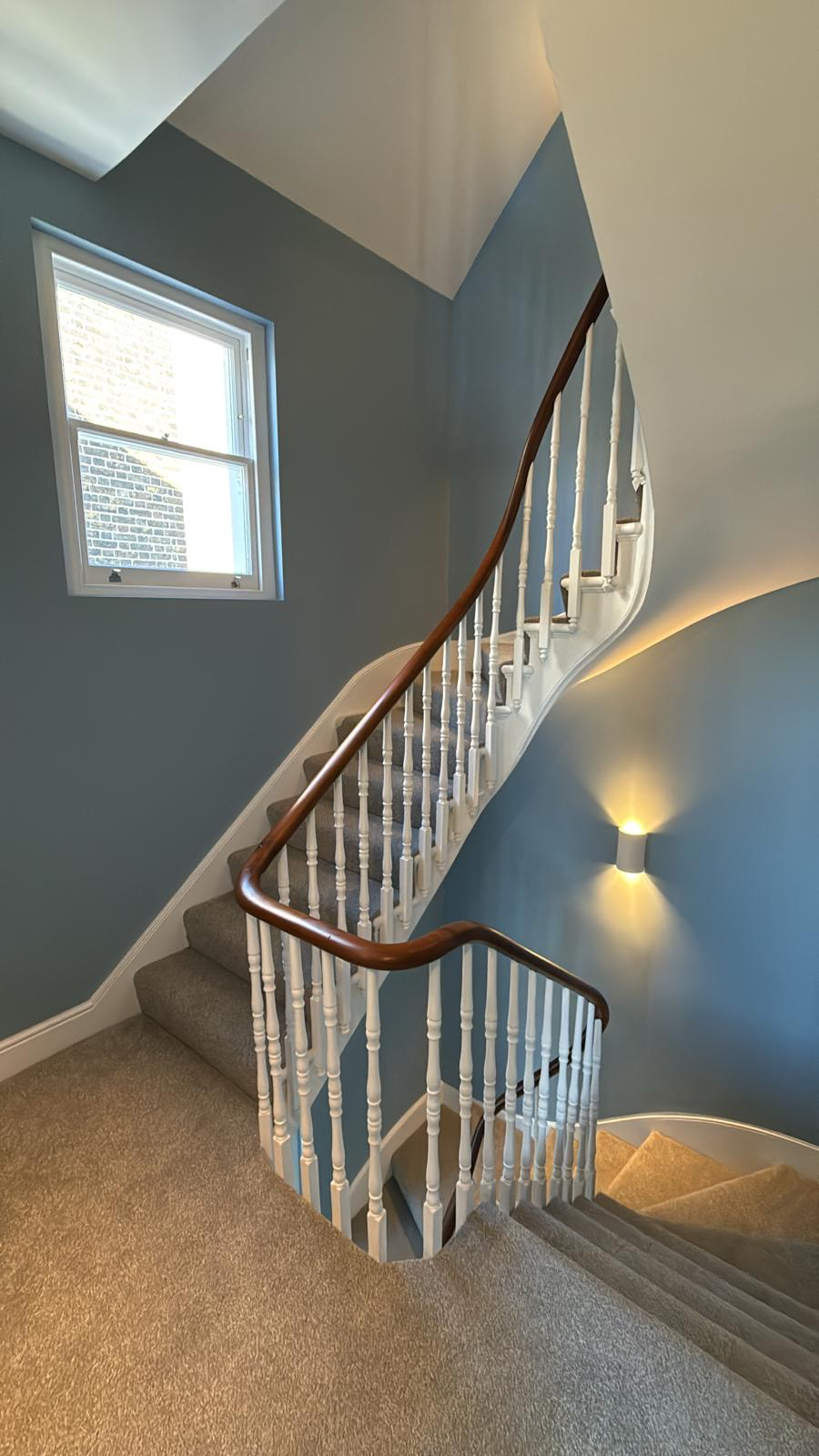 Curved staircase in slate blue with white balusters and new stair carpet