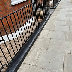 Patio frontage with repainted brick base, black railing and potted planters
