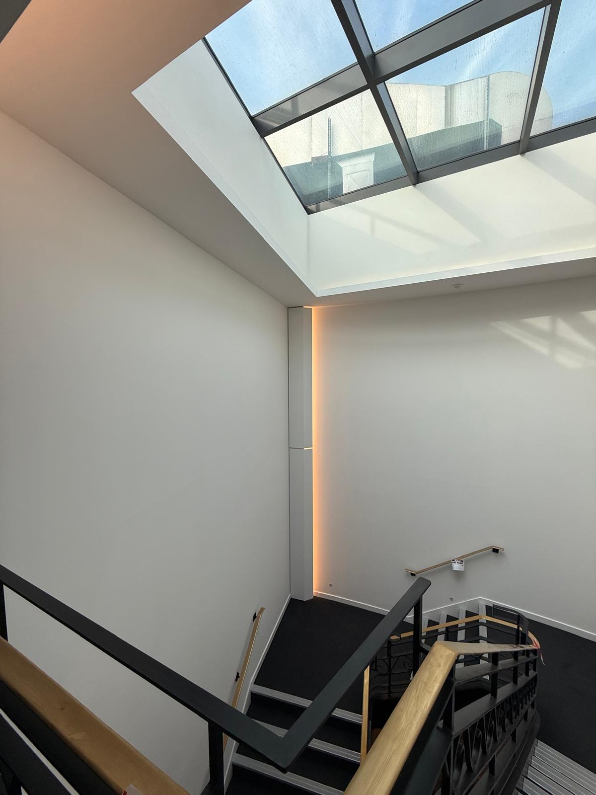 Office stairwell with white walls, glass skylight and LED light recess