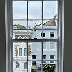 Freshly painted white sash window overlooking neighbouring buildings