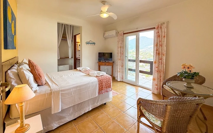 Quarto com cama de casal e varanda com vista para as montanhas