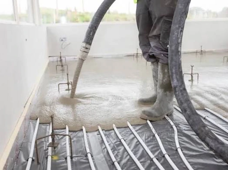 Worker pumping liquid screed onto a floor over underfloor heating — MPC Plastering