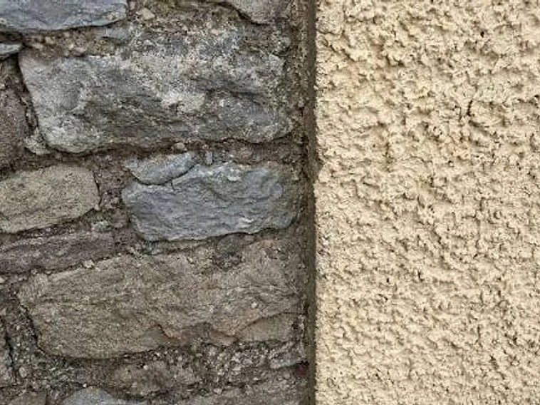 Raw weathered stone beside newly applied lime render — breathability in practice