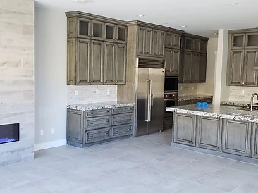 Open-concept living space combining a tiled fireplace feature wall with a fully appointed kitchen and island.