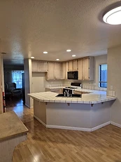 Dated kitchen with light oak cabinets, tiled counters, and black appliances