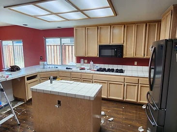 Dated kitchen with red walls, tile counters, and old oak cabinets
