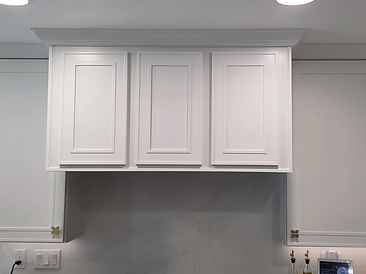 Custom range hood cabinetry with marble slab backsplash and gold flower knobs