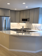 Modern grey shaker kitchen with quartz countertops, seamless backsplash, and under-cabinet lighting