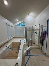Dated bathroom with built-in tub, corner shower, and beige tile during demo prep
