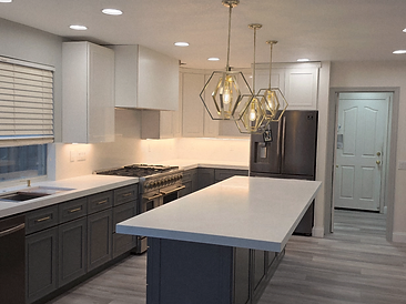 Open-concept kitchen with dark gray island, white uppers, and gold pendant lighting