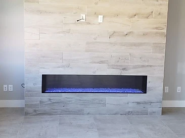 Modern linear electric fireplace built into a floor-to-ceiling wood-look porcelain tile accent wall.