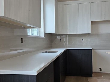 L-shaped kitchen with breakfast bar island — two-tone cabinetry, stainless sink, and polished backsplash.