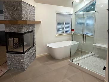 Spa bathroom with freestanding soaking tub, stone fireplace, and glass shower