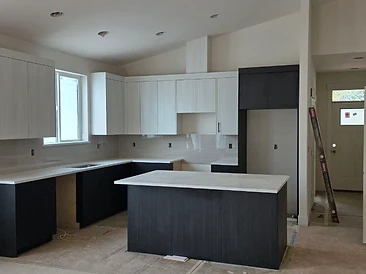 Two-tone kitchen renovation in progress — off-white uppers, charcoal lowers, and white solid-surface countertops.