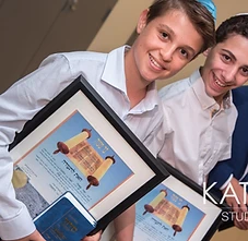 Smiling graduates holding their Bar Mitzvah certificates and Siddurim
