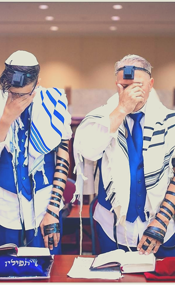 A Bar Mitzvah boy and his father praying together in tallit and tefillin