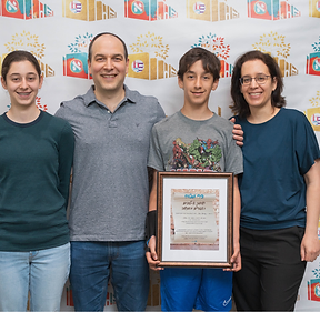 A family posing proudly with their son's Bar Mitzvah certificate