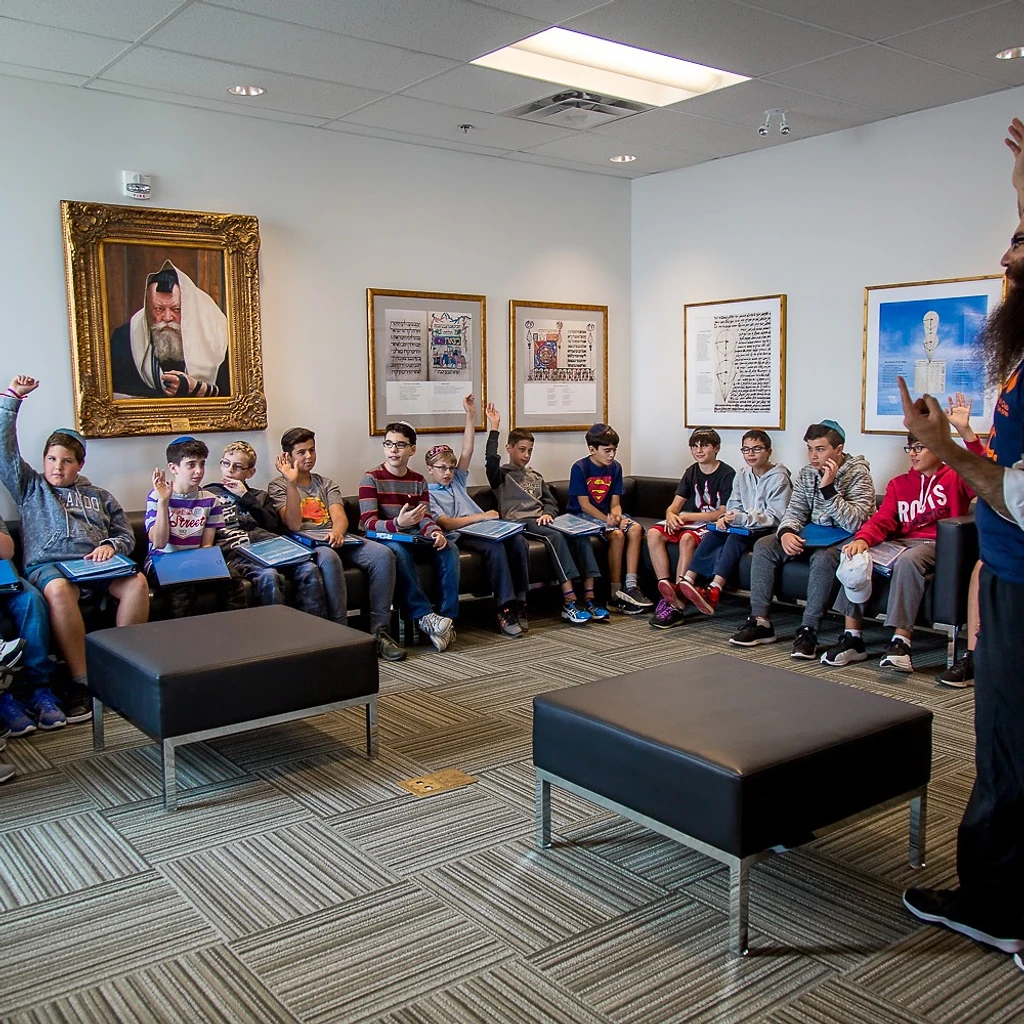 Rabbi Benny leading an energetic BMC session with boys raising their hands