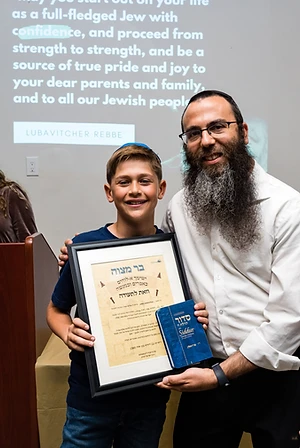 Rabbi Benny presenting a graduate with his Bar Mitzvah certificate