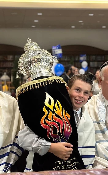 A Bar Mitzvah boy holding the Torah beside his father and grandfather