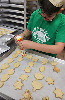 A boy decorating Star of David and dreidel cookies in the BMC kitchen