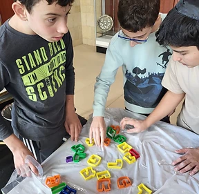 Boys sorting colourful Hebrew letter cookie cutters during a hands-on activity