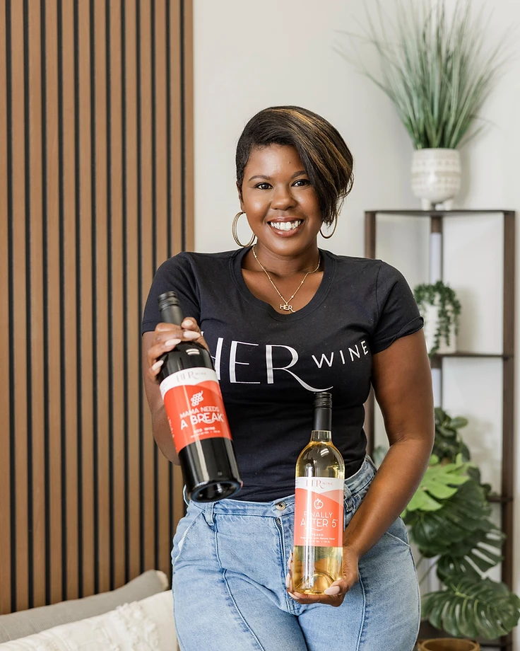 Dr. Nicole Anderson, founder of HER Wine, holding two bottles of HER Wine