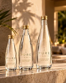 Three PURE by Air glass bottles in different sizes on a sunlit stone surface