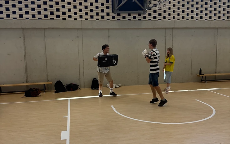 Leerlingen trainen met kickboxpads in een schoolsporthal