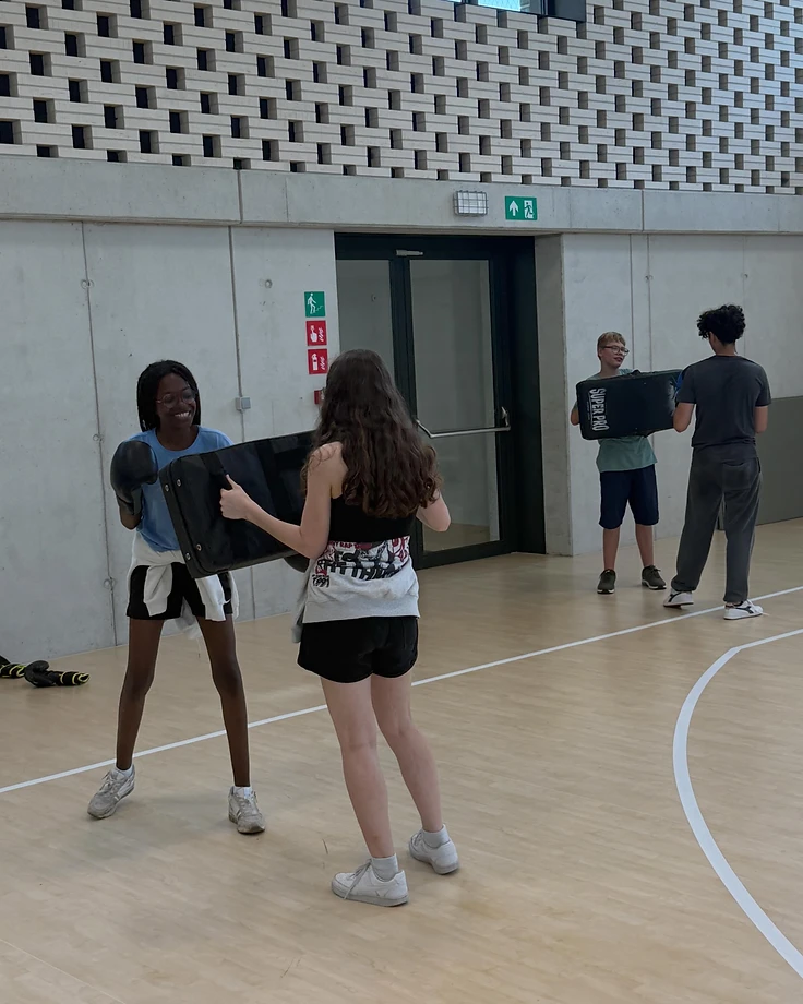 Twee leerlingen oefenen met een kickboksschild tijdens een schoolsessie