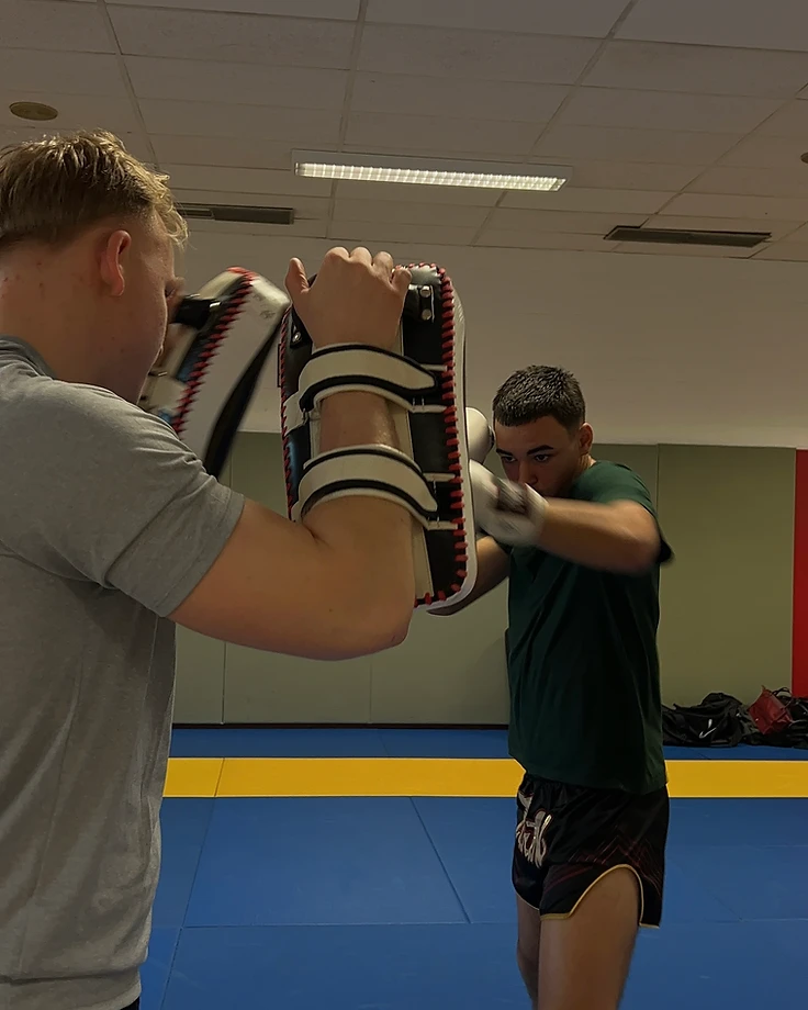 Persoonlijke coach houdt pads voor een leerling tijdens de training