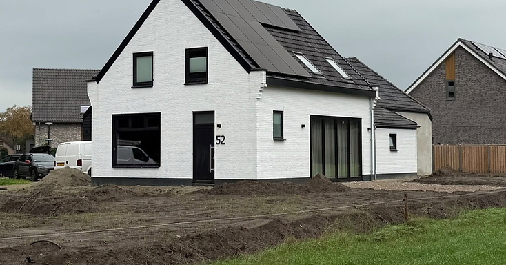 Witte vrijstaande woning met zwarte kozijnen en zonnepanelen op het dak