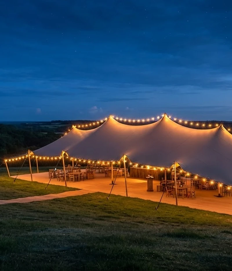 Stretch tent glowing at dusk on a Kent hillside