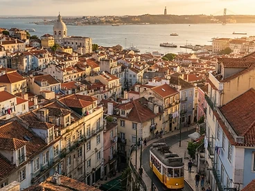 Terracotta rooftops of Lisbon's Alfama district and the Tagus river in warm evening light
