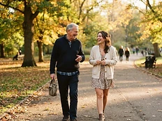 A companion and an older gentleman walking and talking in a park