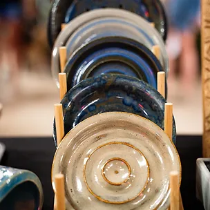 Handcrafted pottery plates in blue and cream glazes on wooden stands