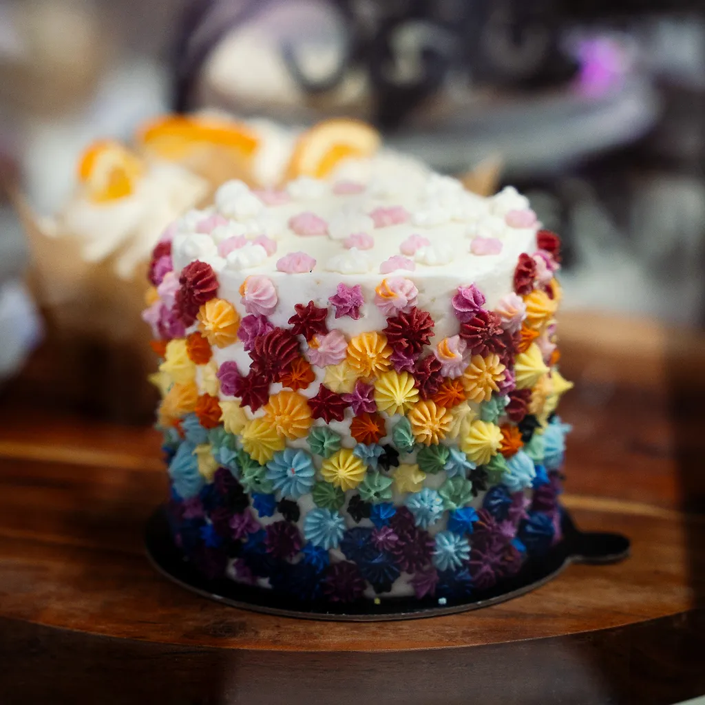 A celebration cake covered in rainbow piped buttercream flowers