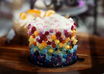 A celebration cake covered in rainbow piped buttercream flowers