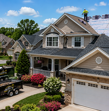 Aerial view of a Jeff's Roofing crew of four replacing shingles on a two-story suburban home with branded truck and dump trailer in the driveway