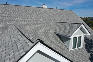 Aerial view of a grey architectural shingle roof with a dormer and gable detail