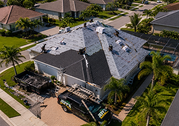 Aerial view of an in-progress roof replacement with crew installing shingles