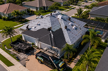 Aerial view of an in-progress roof replacement with crew installing shingles
