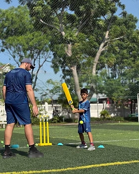 A coach guiding a young batter during a session