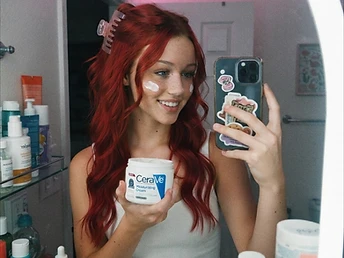 Skylar doing skincare in a mirror