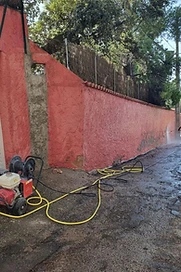 Mur d'enceinte rouge en cours de nettoyage haute pression avant peinture Mur d'enceinte rouge en cours de nettoyage haute pression avant peinture