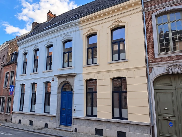 Façade de maison de ville entièrement rénovée et repeinte en bleu clair et jaune après ravalement