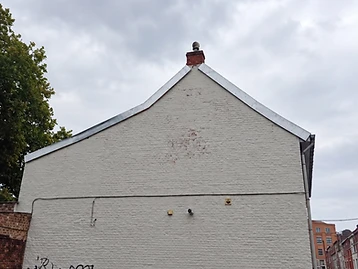 Mur pignon en briques repeint en blanc avec soubassement gris et rives en zinc