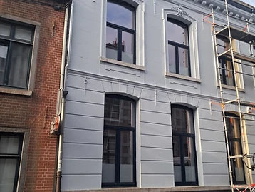 Façade de maison de ville rénovée en gris clair avec moulures et encadrements repeints
